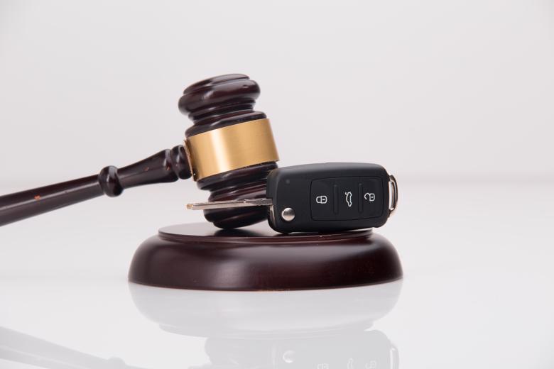 A gavel and car key on a sounding block.